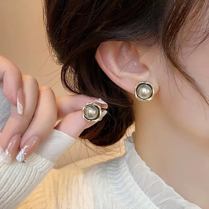 Pair of black pearl stud earrings laid flat side by side
