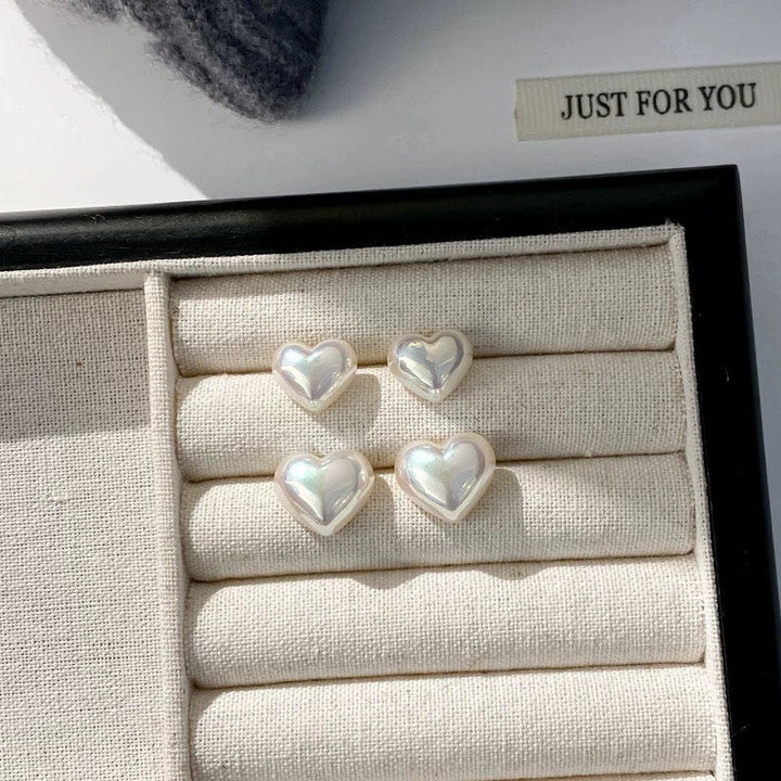 Loving hearts pearl stud earrings displayed on a plain background