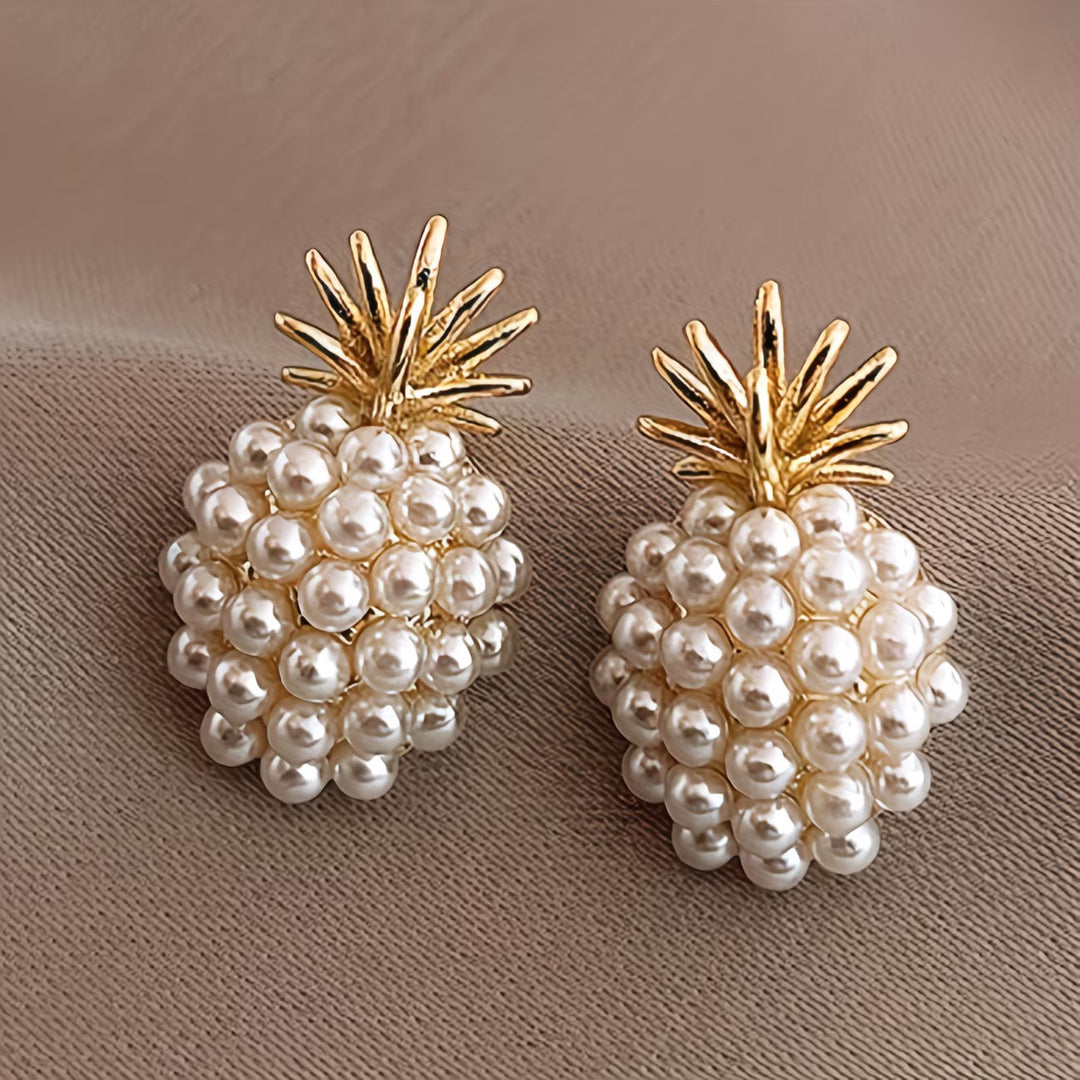 Pearl pineapple drop earrings displayed on a flat lay surface