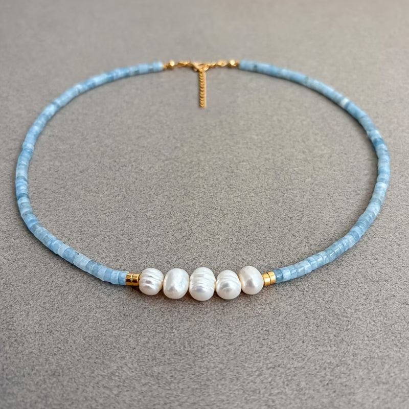 Aquamarine turquoise and pearl necklace laid on a white background