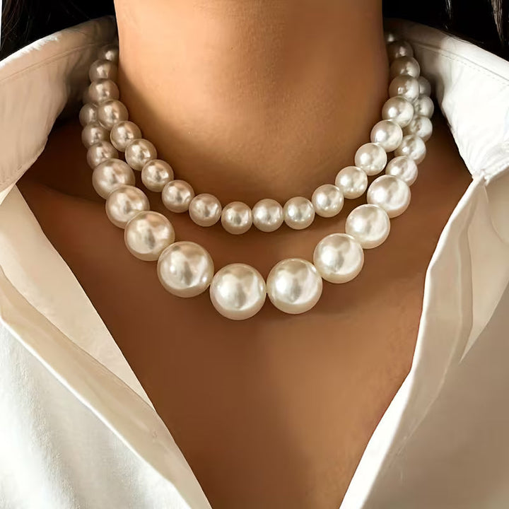 Double statement pearl necklace laid out on a neutral backdrop