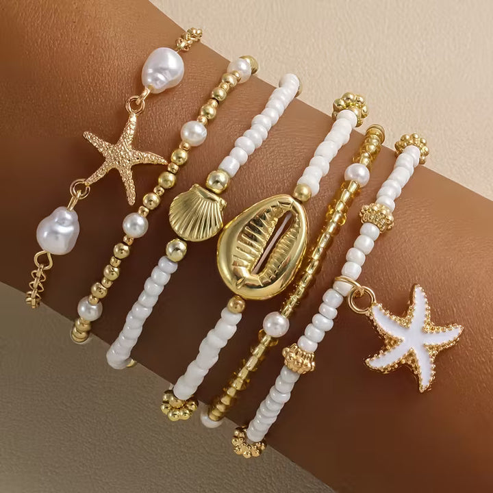 Coastal gold and pearl bracelet set stacked on a wrist