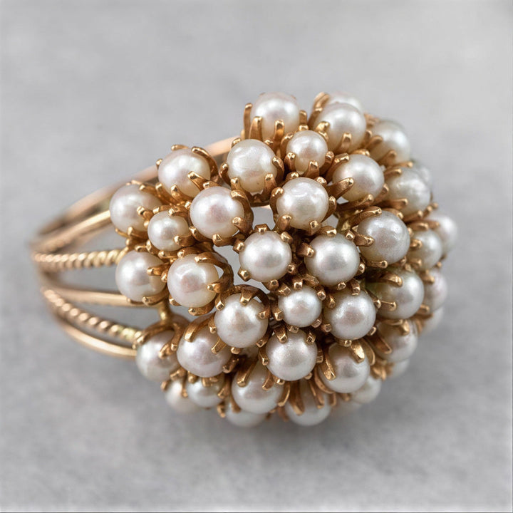 Inlaid pearl ring in gold-tone metal on a white background