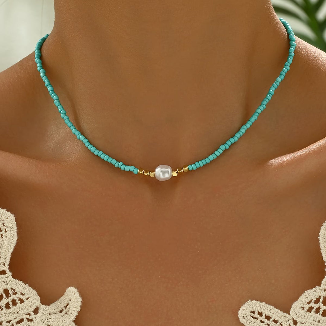 Turquoise and pearl necklace laid flat on a white surface