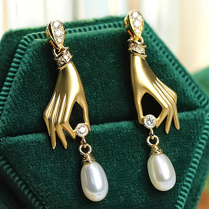 Graceful hand pearl earrings laid flat on a white surface