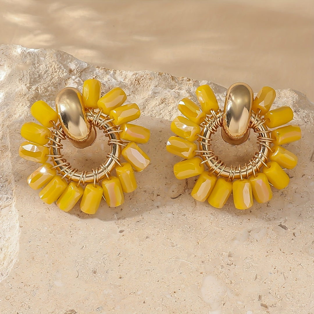 Earrings laid flat beside soft draped fabric