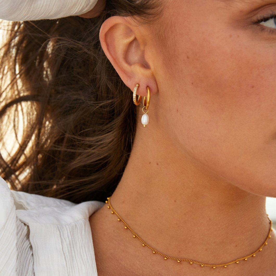 Side profile of a single pearl hoop earring on display