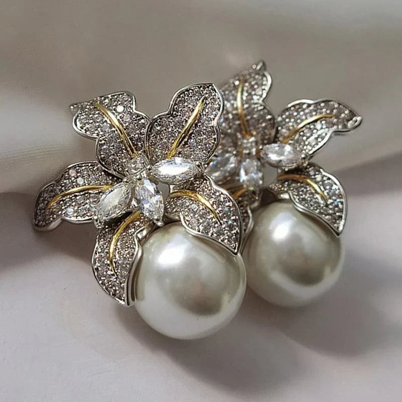 Exquisite flower pearl earrings laid flat on a plain background