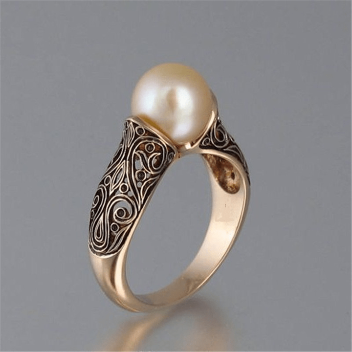 Vintage-style pearl ring in gold-tone metal on a white background
