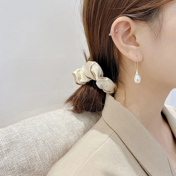 Pearl drop earrings styled next to a jewellery box