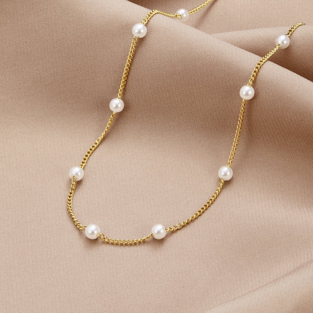 Pearl gold necklace laid flat on a white background