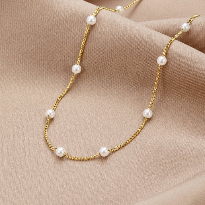 Pearl gold necklace laid flat on a white background