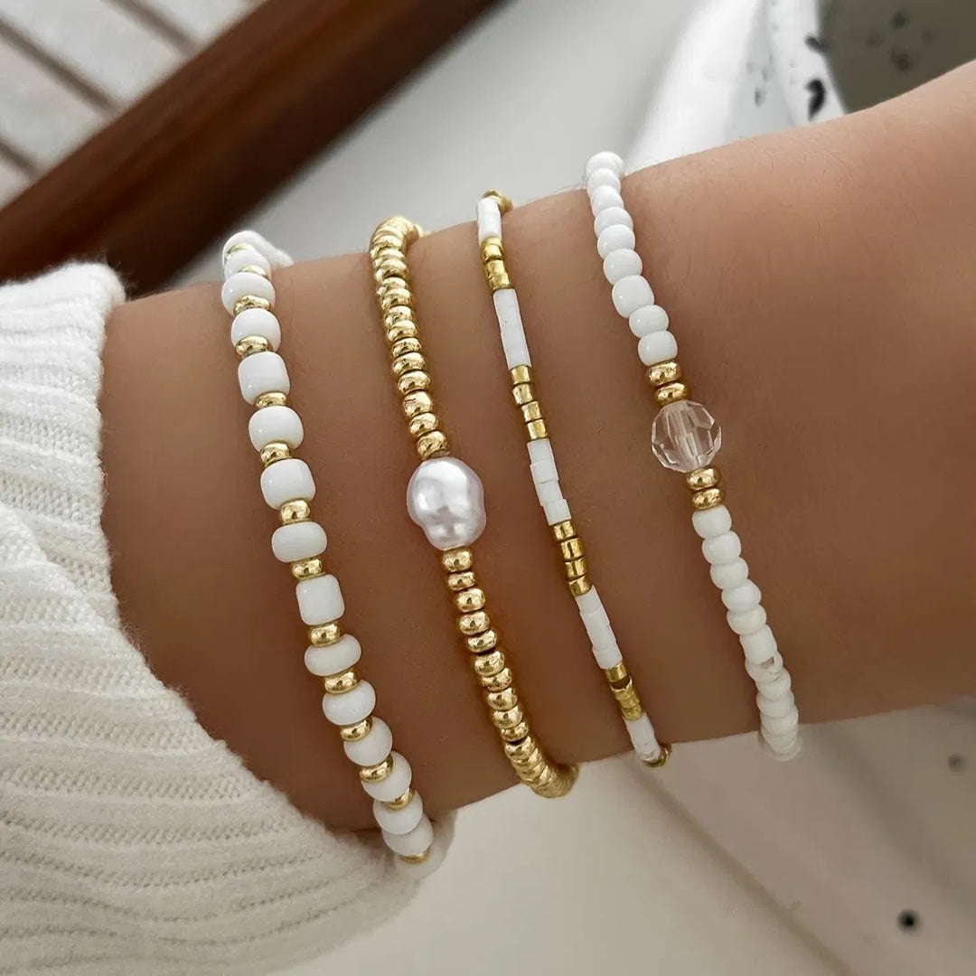 Gold-tone pearl accent bracelet set of four laid flat together