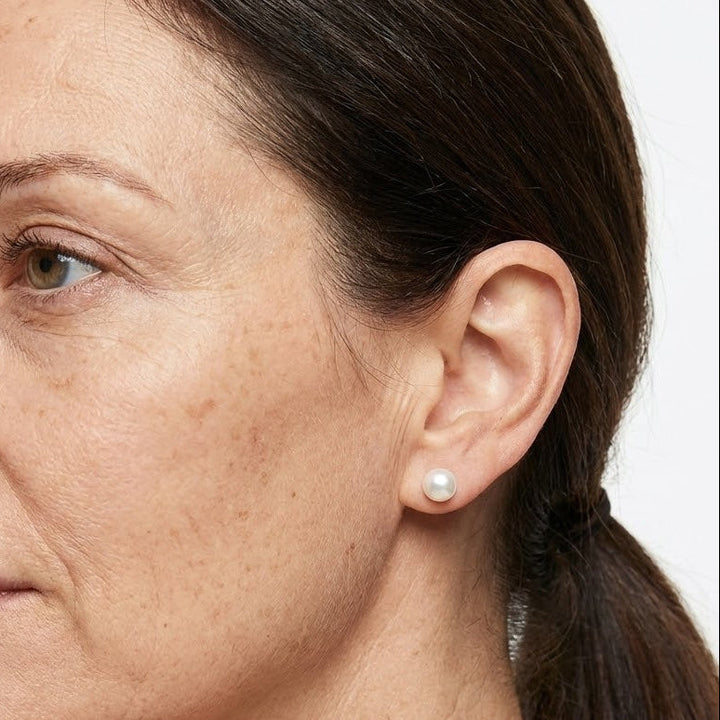 Classic pearl stud earrings worn on a model's ear