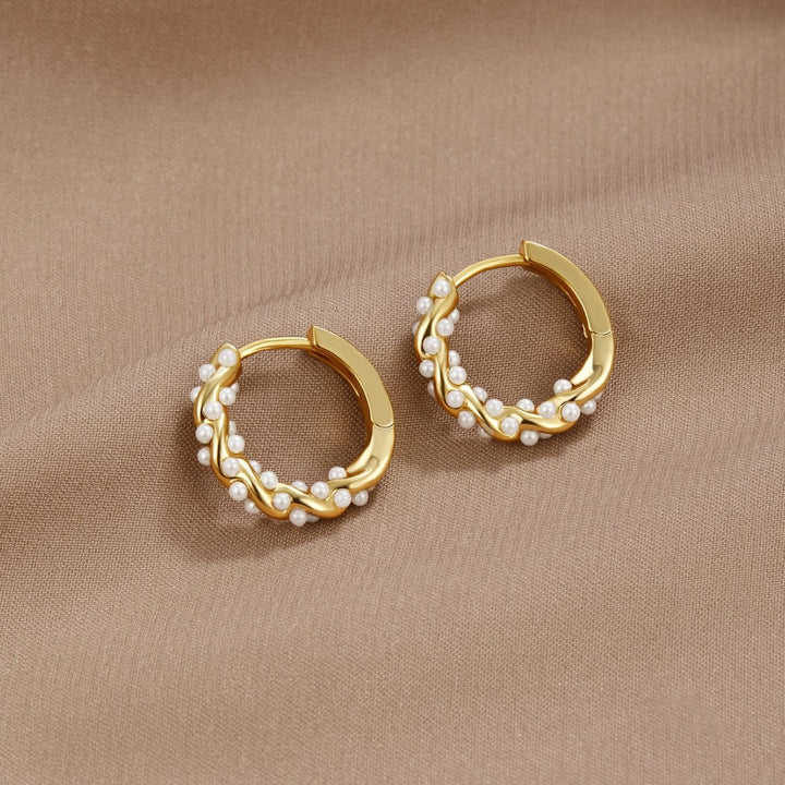 Twirled pearl hoop earrings on a white background